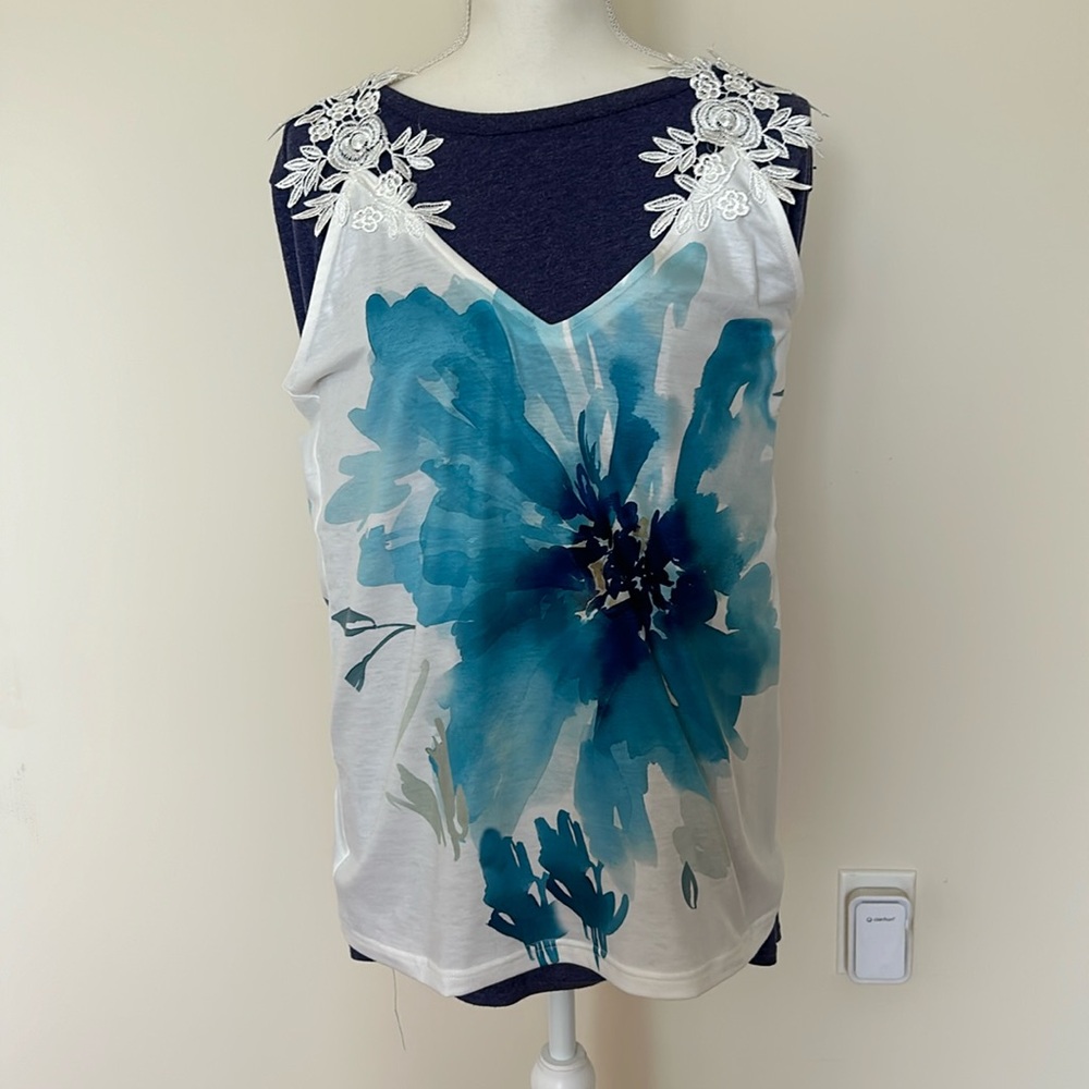 White tank top with blue flower on front and crocheted flower straps.